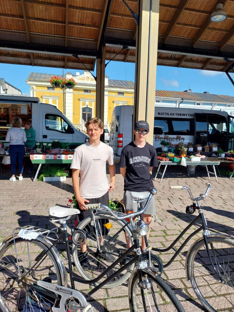 Kaksi kesäyrittäjää pyörävuokraamon polkupyörien kanssa Rauman torilla.