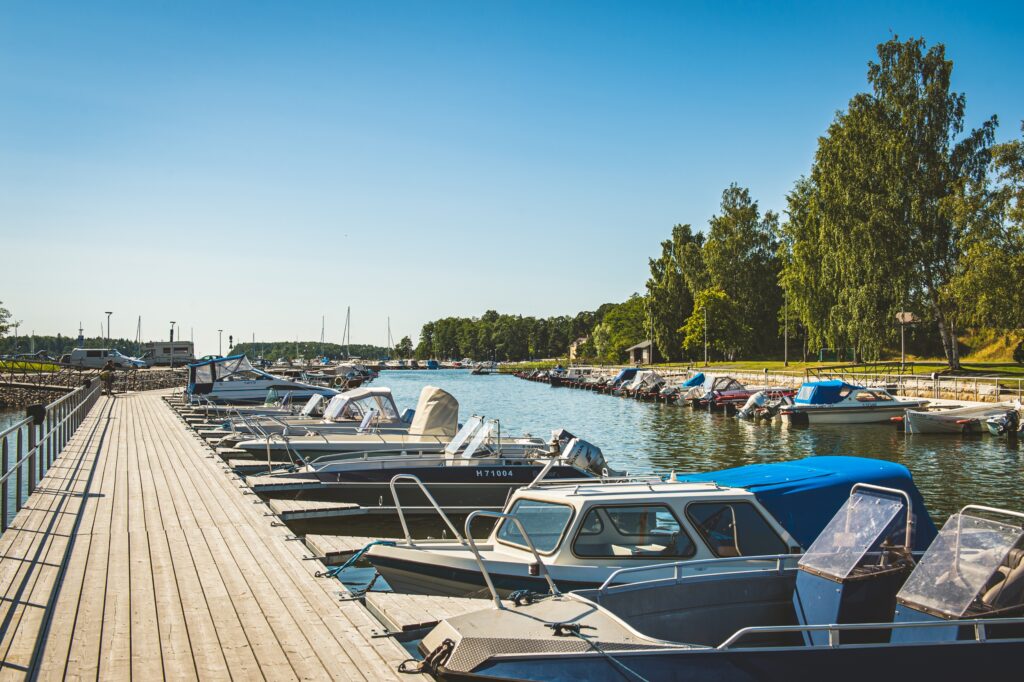Boats moored at a pier in a sunny harbour setting.